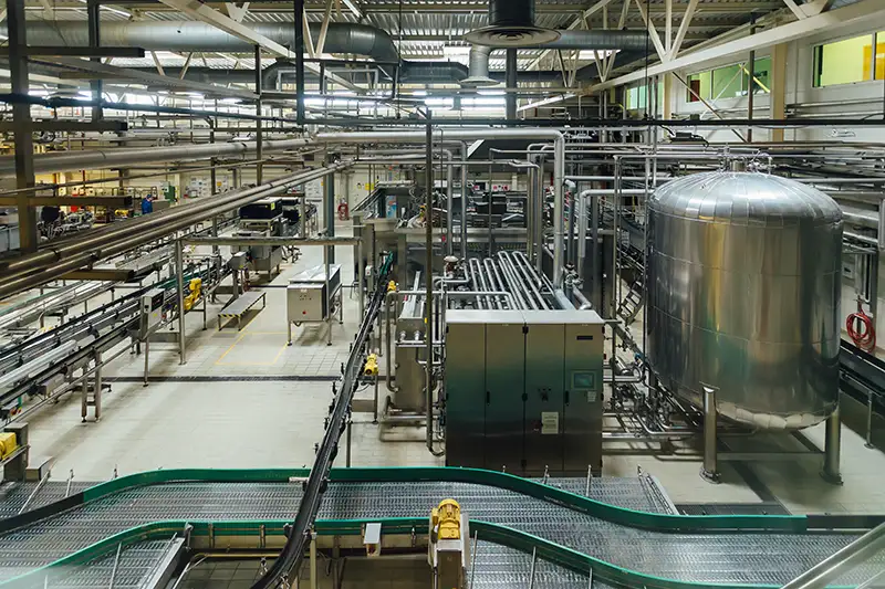 View of the inside of a food processing facility featuring belts and pipes.